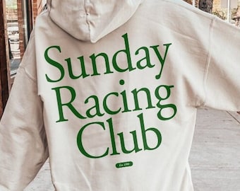 Puede incluir: Una sudadera con capucha de color crema con un gran gráfico verde en la espalda que dice "Sunday Racing Club".