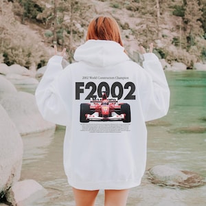 May include: White hooded sweatshirt with a red race car graphic and the text "2002 World Constructor Champion F2002".
