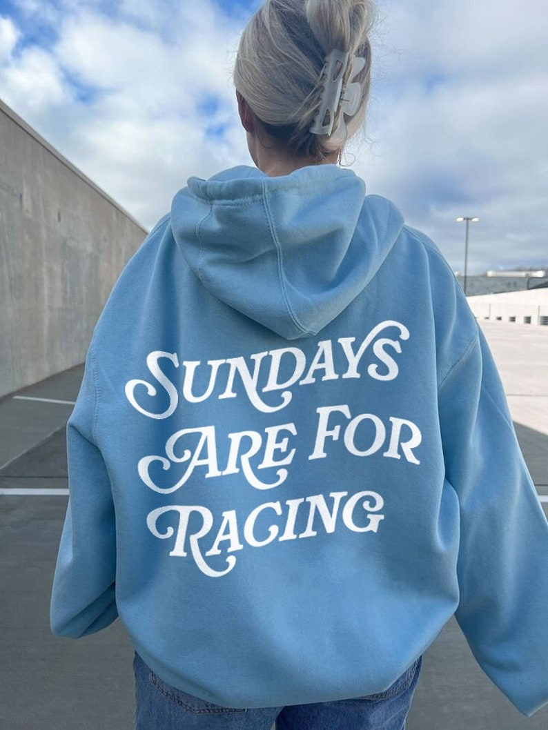 Puede incluir: Una sudadera con capucha azul claro con el texto "Sundays Are For Racing" en letras blancas en la parte posterior.