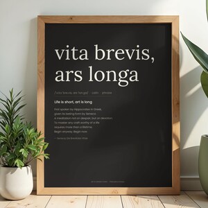 Peut inclure: Une affiche encadrée avec la phrase latine "vita brevis, ars longa" en blanc sur fond noir. La phrase se traduit par "La vie est courte, l'art est long". L'affiche comprend une définition et une citation de Sénèque, encadrée en bois clair.