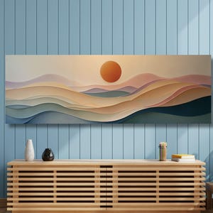 May include: A long rectangular wall art piece featuring a layered landscape of rolling hills in shades of beige, soft pink, and muted blue, with a prominent orange sun centred above the horizon, displayed on a light blue vertical panelled wall.