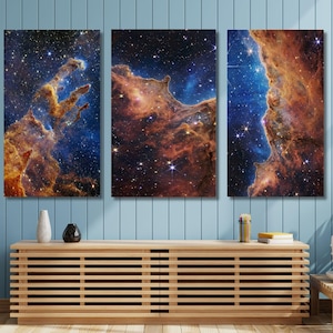 May include: A three-panel wall art set featuring a vibrant space nebula with deep blue and orange gaseous clouds, bright white stars, and cosmic dust formations. The artwork is displayed as a triptych, showcasing intricate celestial details.