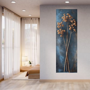 May include: A vertical rectangular wall art piece featuring three dried, light brown plant stems with clusters of small, round seed pods. The stems are set against a textured, deep blue background with subtle variations in tone and shadow.