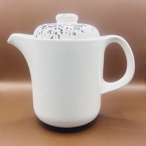 May include: White ceramic teapot with a lid featuring a black and blue splatter design.
