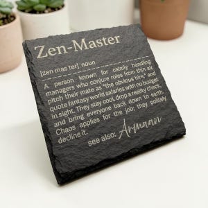 Könnte beinhalten: Ein schwarzer Schieferuntersetzer mit den Worten "Zen-Master" in Weiß eingraviert. Der Untersetzer enthält eine Definition von "Zen-Master" und den Namen "Armaan". Eine einzigartige Geschenkidee.