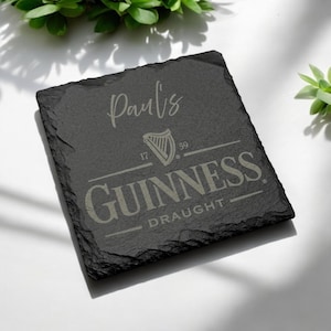 Peut inclure: Sous-verre en ardoise noire avec une inscription blanche qui dit "Paul's" et un logo Guinness gris avec le texte "17 59 GUINNESS DRAUGHT".