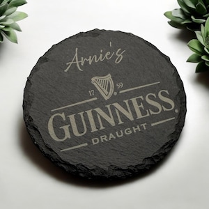 Peut inclure: Un dessous de verre en ardoise noire avec une inscription blanche qui dit "Arnie's" et un logo Guinness avec le texte "GUINNESS DRAUGHT" en blanc.