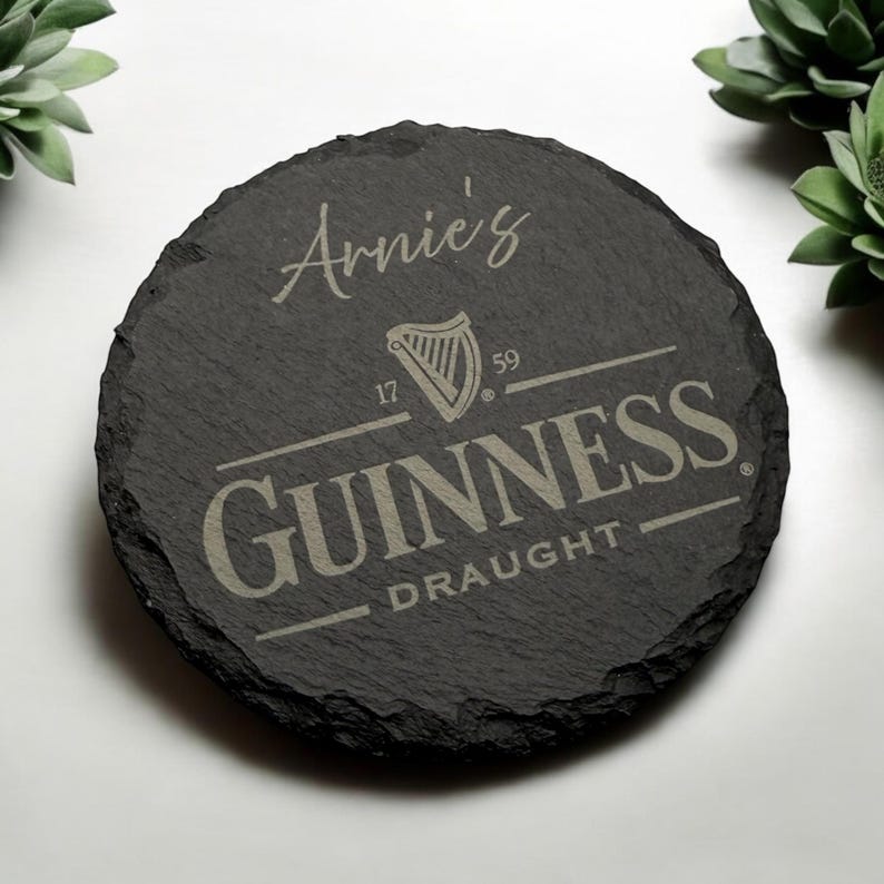 Peut inclure: Un dessous de verre en ardoise noire avec une inscription blanche qui dit "Arnie's" et un logo Guinness avec le texte "GUINNESS DRAUGHT" en blanc.