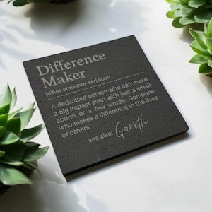 May include: Black slate plaque with the definition of "Difference Maker" and the name "Gareth" inscribed in white.