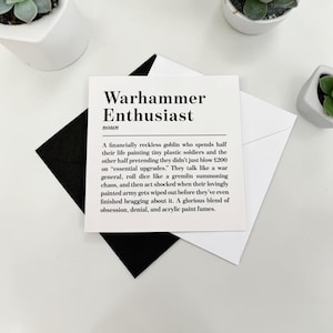 May include: A square white greeting card featuring black text that defines a Warhammer Enthusiast as a financially reckless goblin who spends half their life painting tiny plastic soldiers and the other half blowing £200 on essential upgrades.