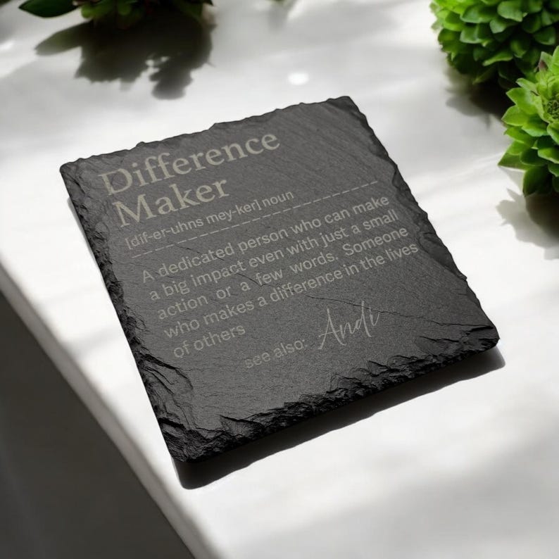 May include: Black slate coaster with the word "Difference Maker" defined as "A dedicated person who can make a big impact even with just a small action or a few words. Someone who makes a difference in the lives of others." The word "Andi" is written in cursive at the bottom.