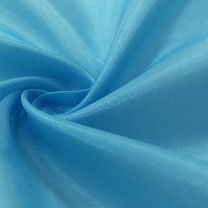 Könnte beinhalten: Nahaufnahme eines glatten, hellblauen Stoffes mit weicher, seidenartiger Textur.