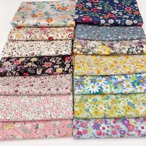 Può includere: Una collezione di tessuti floreali piegati in vari colori. I tessuti presentano una varietà di motivi floreali, tra cui margherite, rose e altri disegni floreali. I colori includono rosa, blu, giallo e bianco.
