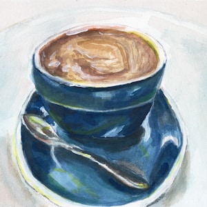Pu&ograve; includere: Una tazza da caff&egrave; in ceramica blu con un piattino e un cucchiaio. La tazza &egrave; piena di caff&egrave; e ha un vortice di schiuma in cima.