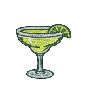 May include: An embroidered patch shaped like a margarita glass filled with a bright lime green liquid. The rim is outlined in white thread to represent salt, and a lime wedge garnish in light green and dark green sits on the edge of the glass.