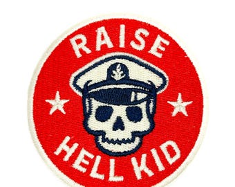 May include: A circular embroidered patch with a bright red background and a white border. The center features a white skull wearing a dark blue captain's hat with an anchor emblem. The text RAISE HELL KID is stitched in white, with two white stars.