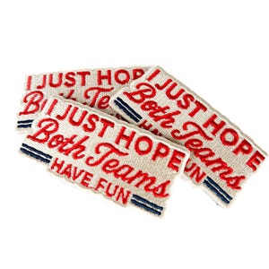 K&ouml;nnte beinhalten: Drei rechteckige Aufn&auml;her mit dem gestickten Text "I JUST HOPE Both Teams HAVE FUN" in roter Farbe. Die Aufn&auml;her sind cremefarben mit blauen Streifen.