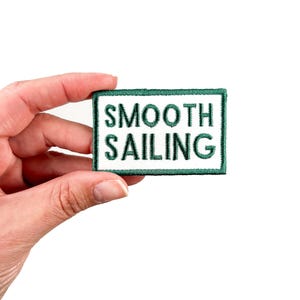 May include: A white patch with green embroidered text that reads "SMOOTH SAILING".