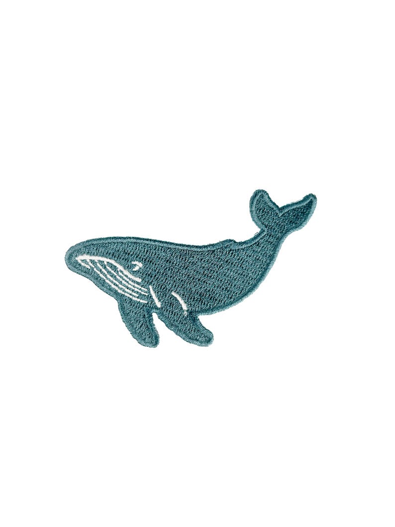 May include: A teal embroidered whale patch. The whale is depicted in a side profile, with a curved body, a small fin, and a detailed tail. White stitching accents the whale's belly and mouth. The patch is designed to be sewn onto fabric.