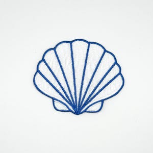 Peut inclure: Un écusson brodé en forme de coquillage blanc avec un contour bleu et des lignes intérieures bleues. L'écusson a la forme d'une coquille Saint-Jacques, avec un design détaillé. L'écusson est sur fond blanc.