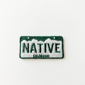Könnte beinhalten: Grün-weißer gestickter Aufnäher mit dem Wort "NATIVE" und dem Text "COLORADO" darunter.