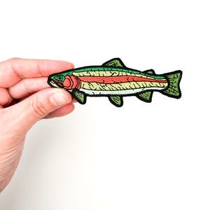May include: An embroidered patch of a rainbow trout fish with green, yellow, red, and black details.
