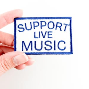 May include: A white patch with blue embroidered text that reads "SUPPORT LIVE MUSIC".