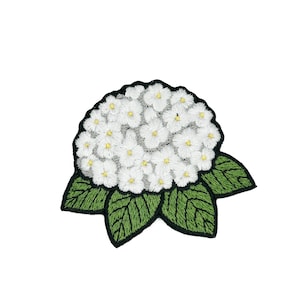 以下が含まれることがあります： 黒い持ち手と「But First, Coffee」のテキストが黒い太字でプリントされた白いセラミックマグ。マグカップはぼやけた背景に置かれており、居心地の良い環境を示唆しています。