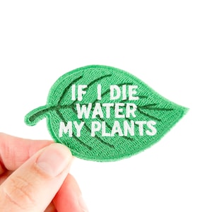 May include: A green leaf-shaped embroidered patch with the text "IF I DIE WATER MY PLANTS" in white. The patch is held by a hand against a white background. The patch is a fun accessory for plant lovers.