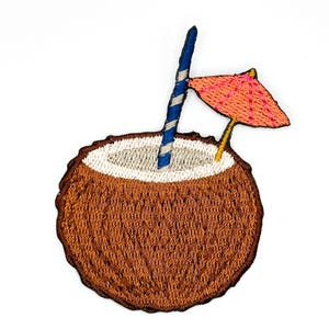 以下が含まれることがあります： 茶色のココナッツの殻に入った飲み物を描いた刺繍ワッペン。白い内側、青と白のストライプのストロー、ピンクのステッチが施された小さなオレンジ色のカクテル傘が、詳細な糸の刺繍で表現されています。