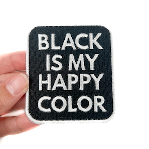 May include: Black square patch with white embroidered text that reads "BLACK IS MY HAPPY COLOR". The patch has a black background with a white border.