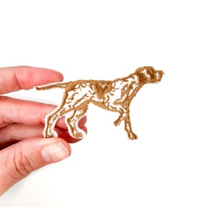 May include: Brown embroidered iron-on patch of a dog, possibly a pointer, in a running pose.