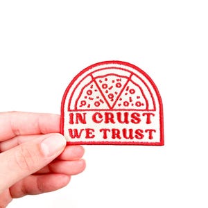 以下が含まれることがあります： ピザのスライスデザインと「In Crust We Trust」というテキストが書かれた赤い刺繍のアイロン接着パッチです。