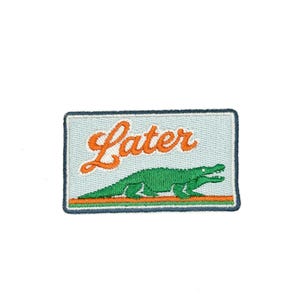 May include: Embroidered patch with a light blue background, featuring the word "Later" in orange script above a green alligator. The patch has a dark blue border and an orange and green stripe at the bottom.