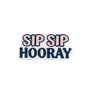 Könnte beinhalten: Gestickter Aufnäher mit den Worten "SIP SIP HOORAY" in Rosa und Marineblau. Der Aufnäher hat einen weißen Rand und ist zum Aufnähen oder Aufbügeln auf Stoff vorgesehen. Der Text ist in einer verspielten Schriftart gehalten.