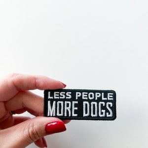 May include: Black embroidered patch with white text that reads "Less People More Dogs".