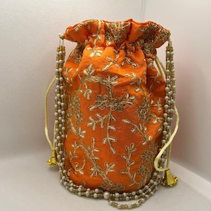 May include: An orange drawstring bag with gold embroidery and a white beaded drawstring. The bag is decorated with a floral pattern.