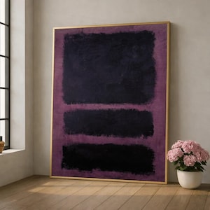 Puede incluir: Una gran pieza de arte mural rectangular que presenta tres bloques negros horizontales de tamaños variados sobre un fondo texturizado de color púrpura intenso, todo encerrado en un marco dorado fino. La pintura muestra pinceladas visibles.