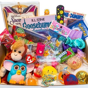 May include: A white box filled with 1990s-themed items including a Snow White VHS, a Goosebumps book, a Furby, a plush monkey, a Ring Pop, a Pokémon card, a nail file, stickers, a Warheads candy, a smiley face pin, and various small plastic toys.