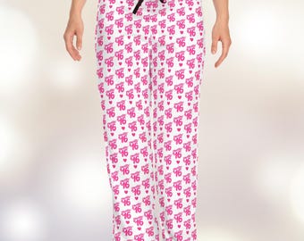 May include: White pajama pants with a repeating pattern of the words "Sweet 16" in pink, along with small pink hearts. The pants have a black drawstring at the waist.