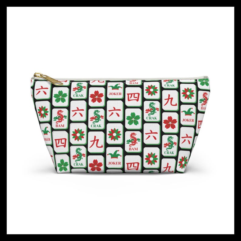 May include: A white cosmetic bag with a gold zipper, featuring a repeating pattern of Mahjong tiles in red, green, and black. The tiles display various symbols and characters, including dragons, flowers, and numbers.