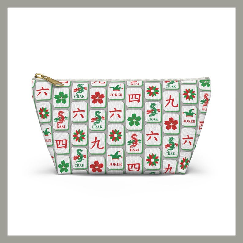 May include: A white zippered pouch with a repeating pattern of Mahjong tiles in red, green, and black. The tiles feature various symbols and characters, including dragons, flowers, and numbers. The zipper is gold.