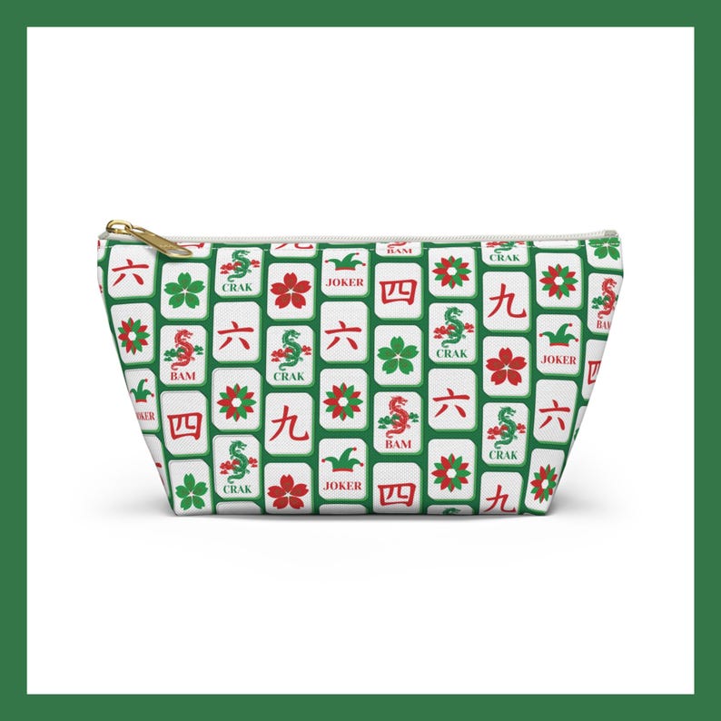 May include: A white zippered pouch featuring a repeating pattern of Mahjong tiles in green, red, and white. The tiles display various symbols and characters, including flowers, dragons, and numbers. The pouch has a gold-colored zipper.