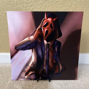 May include: A person wearing a blue suit and a red mask with a scream face. The mask has horns and a white collar. The person is holding a phone to their ear and has a chain around their neck.