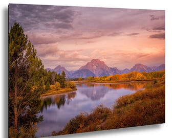 Puede incluir: Impresión de un paisaje con un río que refleja el cielo y las montañas. El cielo es una mezcla de rosas y púrpuras, con el sol poniéndose sobre las montañas. Los árboles son una mezcla de verde y dorado.