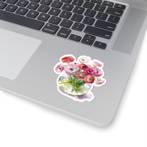 Pode incluir: Um autocolante com uma ilustração em aquarela de um buquê de flores de ranúnculos rosa, vermelhas e brancas em um vaso de vidro transparente. O autocolante está em um laptop prateado.