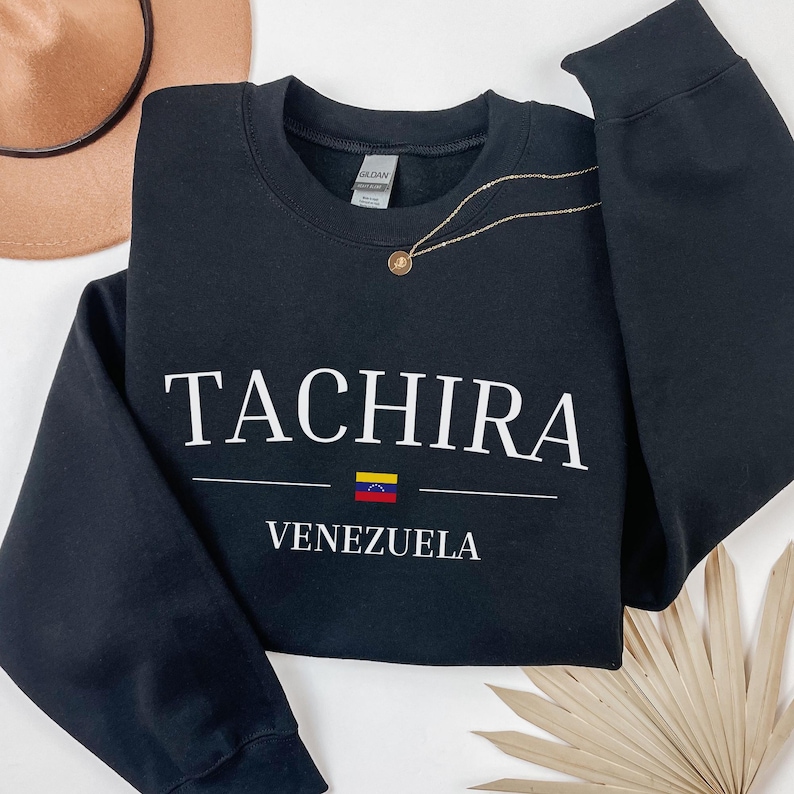 Pu&ograve; includere: Felpa nera con testo bianco che recita "TACHIRA VENEZUELA" e una piccola grafica della bandiera venezuelana.