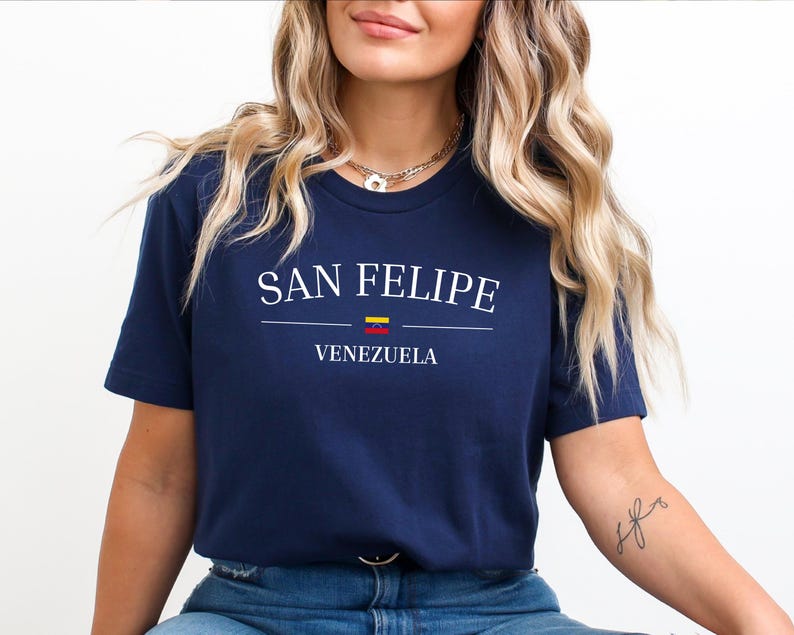 May include: Navy blue t-shirt with the text "SAN FELIPE" in white, with a horizontal line and the word "VENEZUELA" below. A small Venezuelan flag is above the word "VENEZUELA".