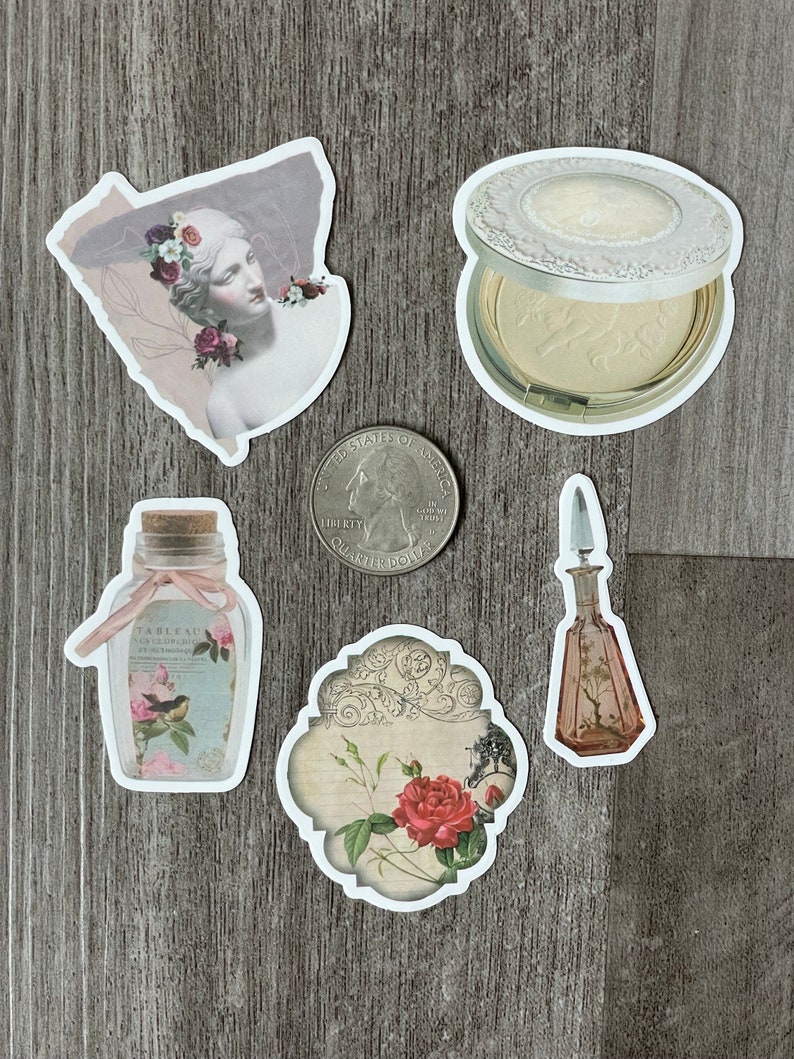May include: A collection of vintage-style stickers featuring a statue with floral accents, a compact, a perfume bottle, a bottle with a bird illustration, and a floral design. A U.S. quarter is also present.