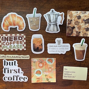 May include: A collection of coffee-themed stickers featuring a croissant, iced coffee, moka pot, and various text designs including I NEED COFFEE PLEASE, HAKUNA MA'COFFEE, Coffee First, Adulting Second, but first, coffee, and No Cappuccino Without the Can-do.